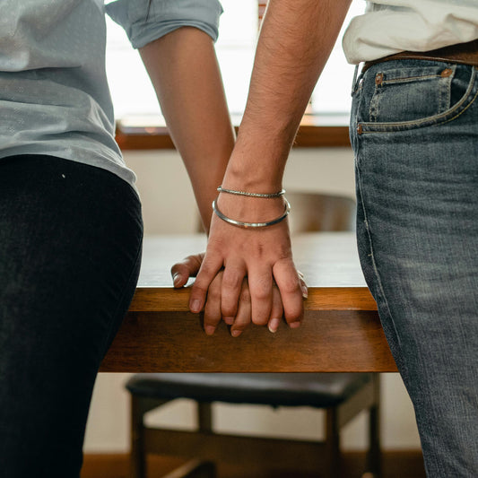 A couple sitting close, sharing a moment of connection. As they hold hands, the story unfolds of how Peachii's Little Pink brings couples closer, embracing intimate moments together.